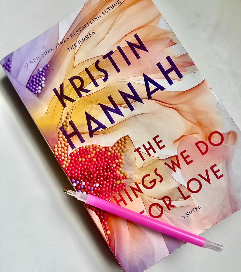 Book titled 'The Things We Do for Love' by Kristin Hannah with a pink pen on a light background